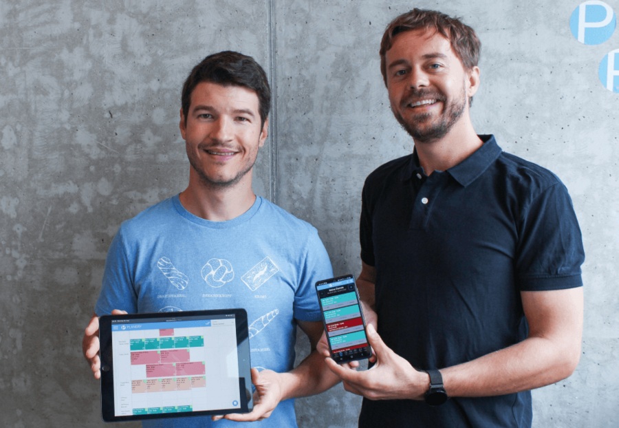 Oliver Raferzeder und Adrian Kaczmarek halten ein Tablet sowie ein Smartphone mit der Planery-App.